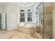 Luxurious bathroom with a walk-in shower, a tub under arched windows, and marble floors at 2503 Regency Lake Dr, Marietta, GA 30062
