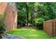 Green backyard with a brick wall, stone features and a view into a wooded area at 3915 Woolbridge Way, Marietta, GA 30062