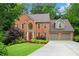 Lovely brick home with a well-manicured lawn, lush trees, and an attached two-car garage at 3915 Woolbridge Way, Marietta, GA 30062