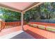 Covered porch with wood flooring, a red railing, wood bench, and a view of the lush backyard at 647 New England Way, Lawrenceville, GA 30046