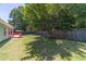 Spacious backyard with mature trees, lush green grass, and a fenced-in area near the cozy back porch at 647 New England Way, Lawrenceville, GA 30046