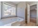 Spacious bathtub in bathroom with window for natural lighting and wooden cabinets at 647 New England Way, Lawrenceville, GA 30046