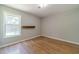 Bright bedroom with a large window, neutral walls, and hardwood flooring showcases a shelf at 647 New England Way, Lawrenceville, GA 30046