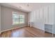 Bright bedroom with wood floors, white paneled accent wall, a large window and built-in shelving units at 647 New England Way, Lawrenceville, GA 30046