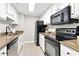Galley kitchen featuring granite countertops, white cabinets, and black appliances at 1280 W Peachtree Nw St # 3208, Atlanta, GA 30309