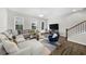 Spacious living room with a large sectional sofa, staircase, and ample natural light at 6370 Cortland Walk, Alpharetta, GA 30005