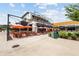Outdoor patio with tables and orange umbrellas for the restaurant Roaring Social at 6370 Cortland Walk, Alpharetta, GA 30005