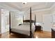 Spacious bedroom with a four-poster bed, tray ceiling, and ensuite bathroom access at 2675 Portabella Ln, Cumming, GA 30041