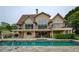 Back exterior of a luxurious home with a pool, stone patio, and manicured landscaping at 2675 Portabella Ln, Cumming, GA 30041