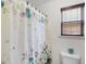 Close-up of a bathroom featuring a floral shower curtain and a window with wooden blinds at 3430 Grand Manor Trl, Snellville, GA 30039