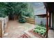 A fenced backyard featuring garden beds and greenery, backing up to mature trees at 3697 E Bay St, Duluth, GA 30096