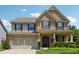 Charming two-story brick home featuring an attached two-car garage, manicured lawn and covered front porch at 4090 Danbury Farms Dr, Cumming, GA 30040