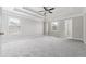 Bright primary bedroom featuring tray ceiling, neutral carpeting, large windows, and a private entry to the walk-in closet at 4090 Danbury Farms Dr, Cumming, GA 30040
