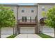 Exterior rear view with garages, wood deck, and well-manicured lawn and landscaping at 2182 Talmai Dr, Snellville, GA 30078