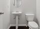 Compact powder room with pedestal sink, oval mirror, and white toilet with dark wood floors at 2182 Talmai Dr, Snellville, GA 30078