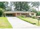 Charming brick ranch home with a long driveway and a covered carport nestled among mature trees at 2614 Princess Se Ln, Marietta, GA 30067