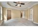 Spacious main bedroom featuring a tray ceiling with ceiling fan and neutral carpeting at 3641 Ridge Towne Dr, Duluth, GA 30096