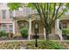 Inviting brick townhouse with a covered porch, complemented by lush landscaping and a charming tree at 4358 Grove Field Ct, Suwanee, GA 30024