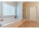 Bright bathroom features a large soaking tub under a window and a separate glass-enclosed shower at 1031 High Tide Ct, Loganville, GA 30052