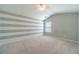 Spacious bedroom with vaulted ceiling, striped accent wall, neutral carpet, and a window with blinds at 1031 High Tide Ct, Loganville, GA 30052