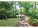 Lush backyard with mature trees, a stone pathway, and fenced perimeter, offering privacy and natural beauty at 1295 Lindenwood Ne Ln, Brookhaven, GA 30319