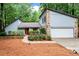 A well-maintained home with stone details, a red door, beautiful landscaping, and an attached garage at 895 Fawn Way, Marietta, GA 30068