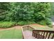 View from wooden deck down to the backyard with lush greenery and grass at 223 Oak Grove Dr, Dallas, GA 30157
