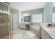 Bright bathroom featuring a glass enclosed shower, and a soaking tub with tile surround at 223 Oak Grove Dr, Dallas, GA 30157