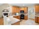 Bright kitchen with wood cabinets, black appliances, tile flooring, and a view into the living room with fireplace at 223 Oak Grove Dr, Dallas, GA 30157
