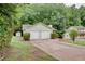 View of the home and its two-car garage nestled in a wooded lot and green yard at 3960 Rocmar Dr, Snellville, GA 30039