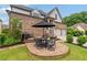 Round brick patio features a table and chairs with a black umbrella, gas grill, and lush green grass at 4224 Dogwood Bend Park, Duluth, GA 30096