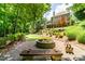Expansive backyard with a stone fire pit, wooden benches, and meticulously landscaped garden beds at 702 Crescent Cir, Canton, GA 30115