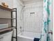 Bathroom featuring a shower over tub, complemented by white tiles and a shelving unit for added storage at 702 Crescent Cir, Canton, GA 30115