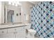 Bathroom featuring a granite-topped vanity with double sinks, toilet, and shower with blue patterned curtain at 702 Crescent Cir, Canton, GA 30115