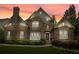 Striking brick and stone exterior with elegant landscaping, bathed in the warm hues of sunset at 702 Crescent Cir, Canton, GA 30115