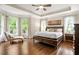 Bright main bedroom featuring tray ceilings, hardwood floors, and large windows at 702 Crescent Cir, Canton, GA 30115