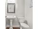 Cozy powder room featuring pedestal sink, dark wood floors, framed mirror and decorative artwork at 702 Crescent Cir, Canton, GA 30115