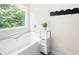 Relaxing bathtub by a large window with a storage shelf in a bright bathroom at 1417 Woodrow Kay Rd, Rockmart, GA 30153