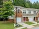 View of townhome featuring manicured lawn, garage, brick facade, and neutral siding at 5057 Lower Elm St, Atlanta, GA 30349