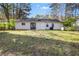 A view of the backyard showing the home's exterior, back door and patio area surrounded by a grassy lawn and mature trees at 5422 Timor Trl, Lithonia, GA 30038