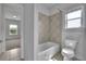 Bright bathroom with a white toilet and a tub with tile surround, perfect for relaxation at 56 Addison Woods Dr, Sugar Hill, GA 30518