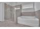 Bright bathroom featuring a glass shower, soaking tub, and gray tiled walls at 56 Addison Woods Dr, Sugar Hill, GA 30518