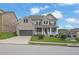 Beautiful two-story home with a manicured lawn, inviting front porch, and two-car garage on a sunny day at 56 Addison Woods Dr, Sugar Hill, GA 30518