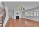 Inviting living room featuring hardwood floors, a fireplace, a ceiling fan, and large windows for natural light at 56 Addison Woods Dr, Sugar Hill, GA 30518