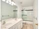 Well lit bathroom includes tile floors, a double vanity, and shower tub combo behind a sliding glass door at 630 Beckenham Walk Dr, Dacula, GA 30019