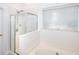 Bright bathroom featuring a shower with glass door and an attached soaking tub beneath a sunny window at 630 Beckenham Walk Dr, Dacula, GA 30019