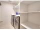 Bright laundry room area featuring shelving for storage, stainless steel washer and dryer at 630 Beckenham Walk Dr, Dacula, GA 30019