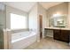 Well-lit primary bathroom with tub, shower, double vanity sinks, and tile floors at 1021 Reddy Farm Rd, Grayson, GA 30017