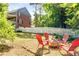 Backyard with fire pit, red Adirondack chairs, white fence and lush green lawn at 4259 Kings Troop Rd, Stone Mountain, GA 30083