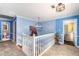 Hallway with blue walls, white trim, chandelier, and view into the downstairs and a nearby bathroom at 4259 Kings Troop Rd, Stone Mountain, GA 30083